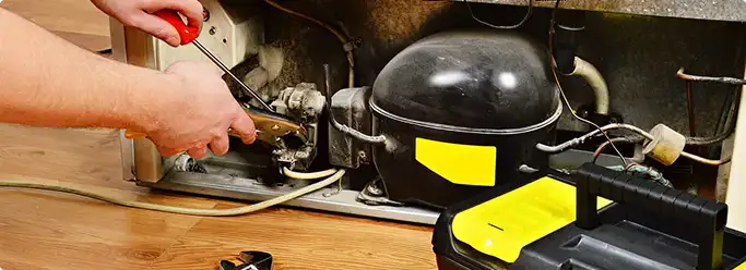 Refrigerator repair technician fixing the compressor and wiring in Leicester, MA