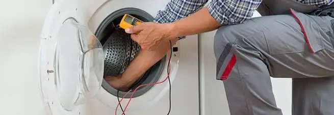 Dryer repair technician inspecting and repairing a clothes dryer in Worcester, MA