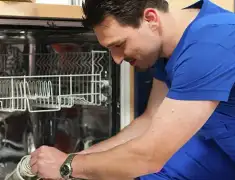 Dishwasher repair technician inspecting and servicing an open dishwasher in Worcester, MA