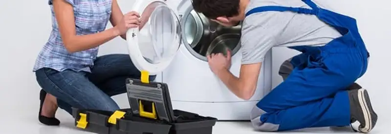 Washer repair technician inspecting a front-load washing machine with tools in Worcester, MA