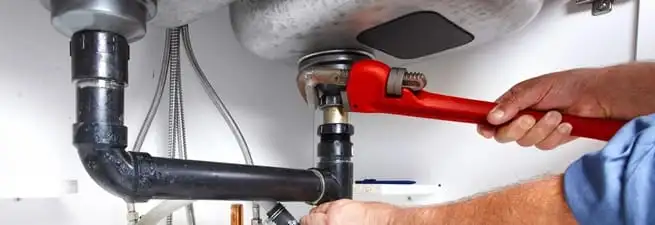 Garbage disposal repair technician tightening the sink drain and disposal connection in Worcester, MA