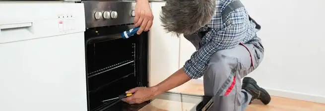 Oven repair technician inspecting and servicing an electric oven in Worcester, MA