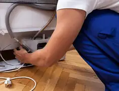 Appliance repair technician fixing refrigerator water line and connections in Worcester, MA