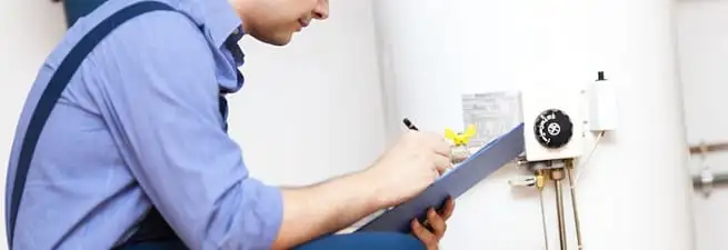 Water heater repair technician inspecting the unit and recording service notes in Worcester, MA