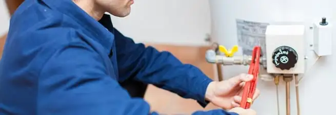 Water heater repair technician adjusting the temperature control and gas valve in Worcester, MA